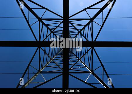 A low angle shot of a power line tower under a clear blue sky Stock Photo