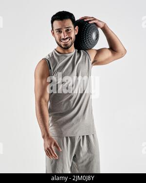 Be strong, positive and full of beast mode. Studio portrait of a muscular young man holding an exercise ball against a white background. Stock Photo