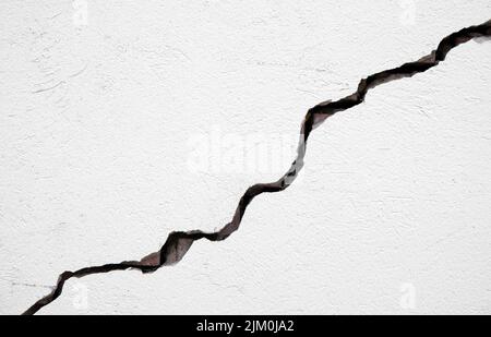 Long deep crack on the damaged wall as texture or background Stock Photo