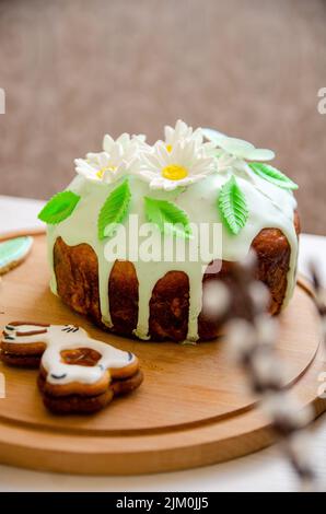 Vertical shot of an Easter bunny cookie and Ukrainian Easter bread (Paska Easter bread) on a round wooden plate Stock Photo