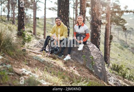 Friends who experience nature with you are keepers. Full length portrait of two young athletes sitting together after a morning run through the woods. Stock Photo