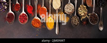 Various spices in vintage spoons on stone table. Top view flat lay Stock Photo