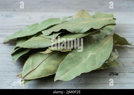 Dried whole bay leaves on cutting board (Laurus nobilis) Stock Photo