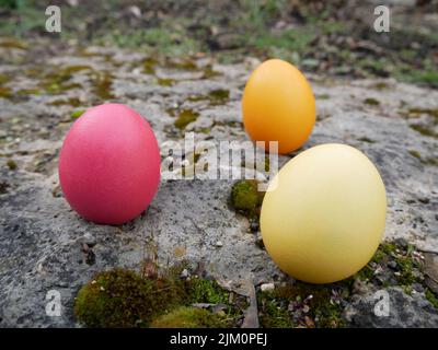 Three colored easter eggs on a stone Stock Photo