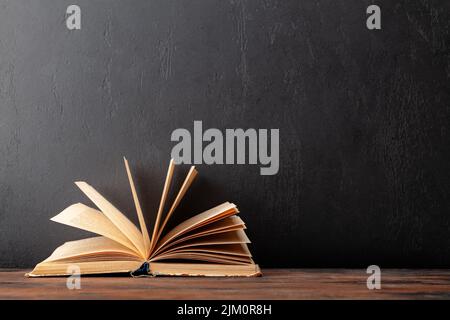 Open old book on wooden table and blackboard for copy space. School and education template Stock Photo