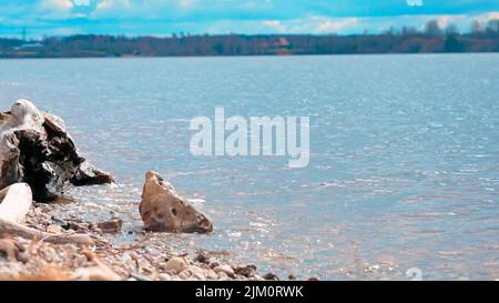 A bright summer day at the beach with small abstract-shaped rocks on the shore Stock Photo