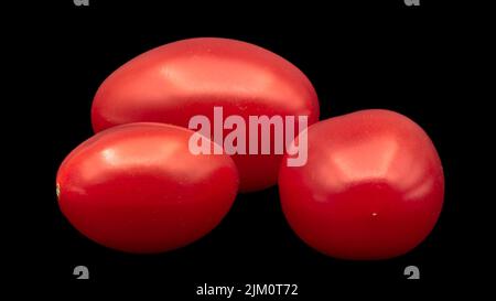 A closeup of cherry tomatoes isolated on a black background Stock Photo