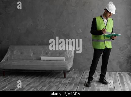 Arab foreman builder, engineer or inspector in safety vest reflective checking and inspecting with clipboard at construction site building interior Stock Photo