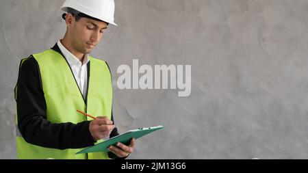 Serious Arab engineer taking note on clipboard, banner Stock Photo