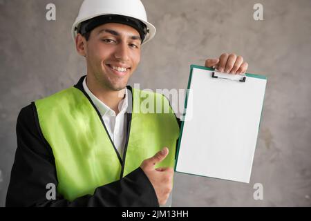 Engineer in a hard hat with a blank clip board in his hands, a place for advertising text Stock Photo
