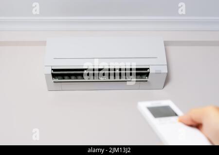 Man's hand with remote control turning on the air conditioner. Stock Photo