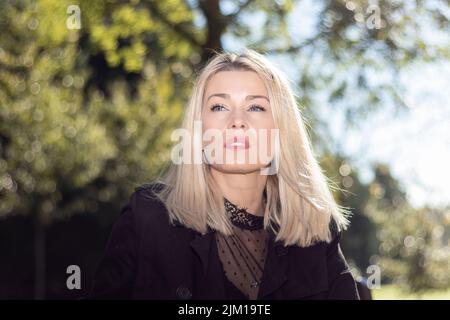 thoughtful blonde woman looking straight ahead in a park Stock Photo