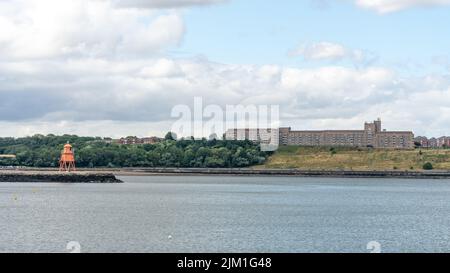 A riverscape view of the Sir James Knott Memorial flats in North Shields, North Tyneside, UK and the Herd Groyne in the River Tyne. Stock Photo