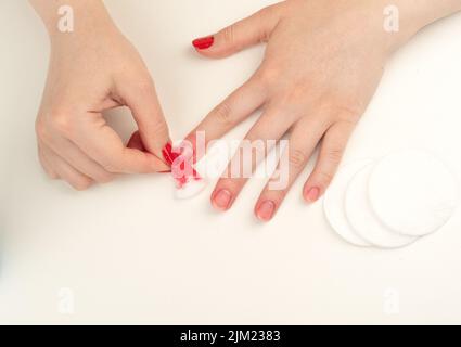 Young woman removes nail polish from her nails with a cotton pad soaked in nail polish remover. Copy space. Stock Photo