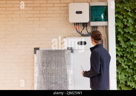 Back view of unrecognizable young man technician installing a solar system for renewable energy with solar panel Stock Photo