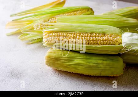 Fresh young sweet corn on cobs on grey table close up, harvest concept Stock Photo