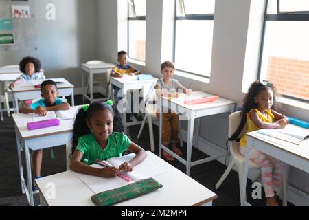 High angle view of multiracial elementary school students sitting at desk in classroom Stock Photo