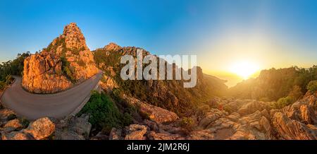 Aerial view of a tourist woman on top aerial view of sunset badlands Calanques of Piana. Drone view on the road in Corsican badlands called Les Stock Photo