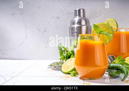 Carrot Ginger Margarita cocktail with lime, mint and hot chili pepper, original vegetable spicy drink on white tiled background copy space Stock Photo