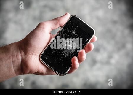 Smart cell phone with a broken screen in hand Stock Photo