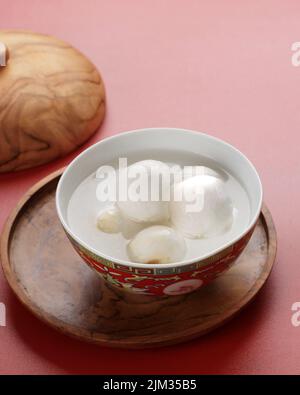 Tang Yuan, Chinese Glutinous Rice Dumpling Balls with Sugar Ginger or Palm Sugar Syrup on Red Chinese on Black Background for Winter Solstice New Year Stock Photo