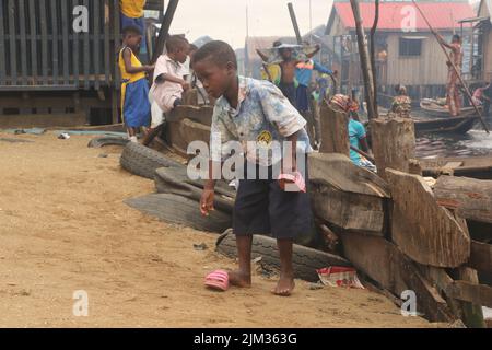 A young school boy plays during break at the Makoko fishing community on the Lagos lagoon. Makoko is a slum community located in Lagos. Established in the 18th century primarily as a fishing village, much of Makoko is made up of structures constructed on stilts, on the edge of the Lagos Lagoon. Nigeria. Stock Photo