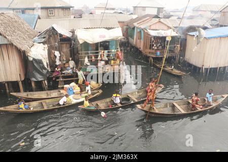 Residents and petty traders in a canoe sell goods at the Makoko fishing community on the Lagos lagoon. Makoko is a slum community located in Lagos. Established in the 18th century primarily as a fishing village, much of Makoko is made up of structures constructed on stilts, on the edge of the Lagos Lagoon. Nigeria. Stock Photo