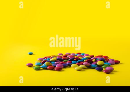 Pile of multi colored chocolate candies with copy space on yellow background Stock Photo