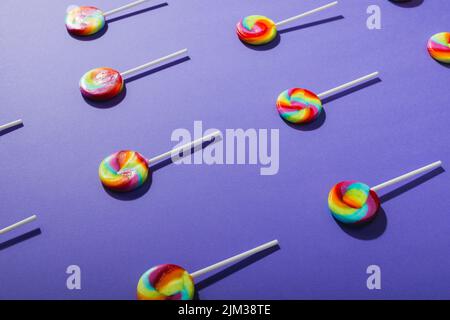 High angle view of multi colored lollipops arranged in row on blue background Stock Photo