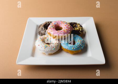 High angle view of fresh donuts in white plate on beige background Stock Photo