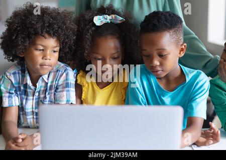 African american elementary students using laptop while sitting at desk during computer class Stock Photo