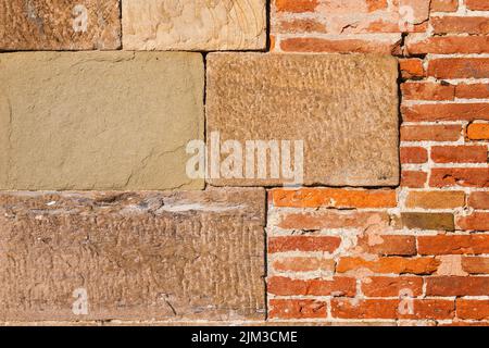 Ancient composite stone wall with red bricks as background Stock Photo