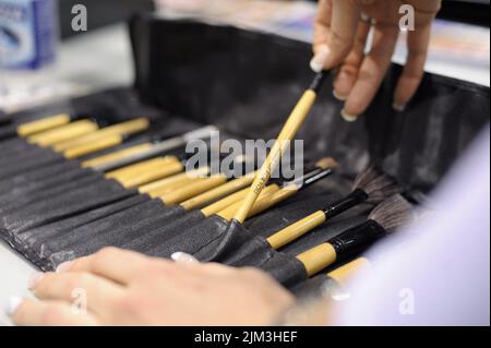 The girl is removing a makeup brush from a set of brushes from a black leather bag Stock Photo