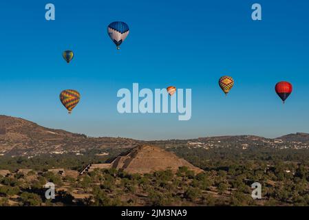 A distant view of colorful hot air balloons flying over the Pyramid of the Sun in Teotihuacan, Mexico Stock Photo