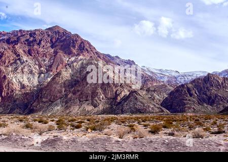 Brown mountains and blue sky in Mendoza, Argentina, South America. Snowy mountains in the background. Landscape in Wintertime Stock Photo