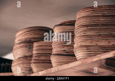 A closeup shot of lines of Old proofing baskets for baking bread on a wooden shelf Stock Photo