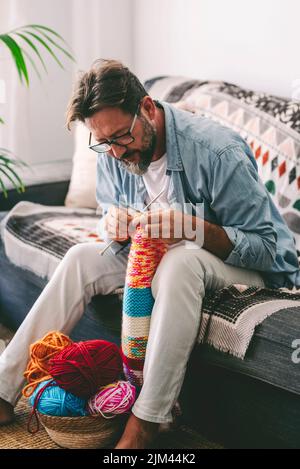 Man doing knit work with needles to relax and enjoy indoor time at home. Hand made work relaxation therapy. People doing hobby or diy leisure activity Stock Photo