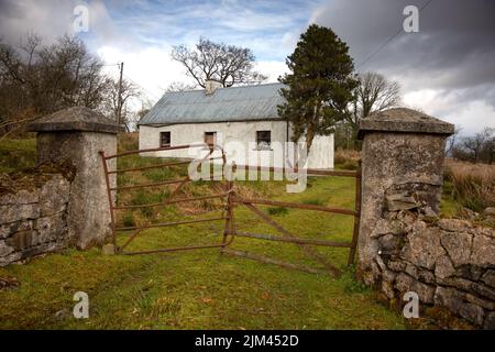 Old abandoned ruined building with grass covered yard against the cloudy sky Stock Photo