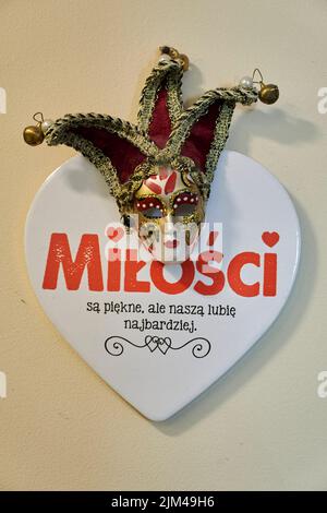 A closeup shot of a Venetian souvenir mask and heart ornament hanging on a wall in Poznan, Poland Stock Photo