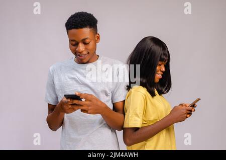 A Happy excited African Couple standing and using phones isolated on gray background Stock Photo