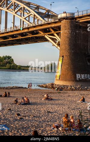 Nijmegen, Gelderland, Netherlands. 3rd Aug, 2022. People are seen enjoying the warm temperatures along the low water level banks of the Waal river. Due to the ongoing drought, the Netherlands officially has a water shortage, the government announced. The scarce water will be distributed according to the legal agreements so that dikes, peatlands, and very vulnerable nature areas are supplied with water for as long as possible. More measures may follow in the coming weeks. With two-thirds of the Dutch population living below sea level, droughts can quickly become an acute problem in the Netherl Stock Photo