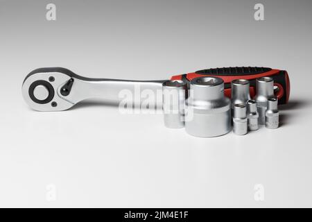Ratchet wrench with hex socket and several interchangeable sockets of different sizes on a white surface Stock Photo
