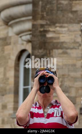 spectator looking through a pair of binoculars at the annual cowes week regatta on the isle of wight, sailing and yachting regatta spectator at cowes. Stock Photo