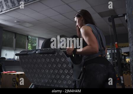 Low angle shot of a female bodybuilder putting weights on leg press machine Stock Photo