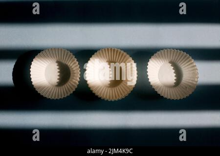 empty baking paper cups. white cookie paper cases isolated on blue background with shadow Stock Photo