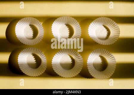 empty baking paper cups. white cookie paper cases isolated on yellow background with shadow Stock Photo