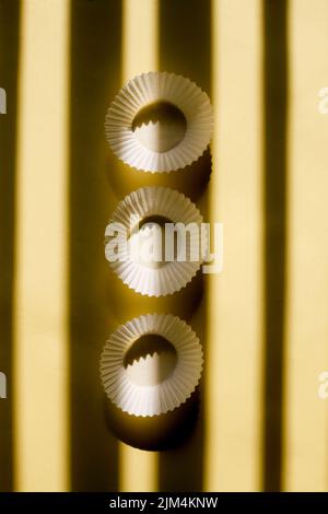 empty baking paper cups. white cookie paper cases isolated on yellow background with shadow Stock Photo