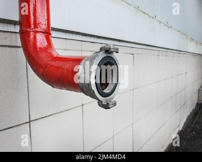 Red fire-fighting pipeline with a lock close-up on a tile background Stock Photo