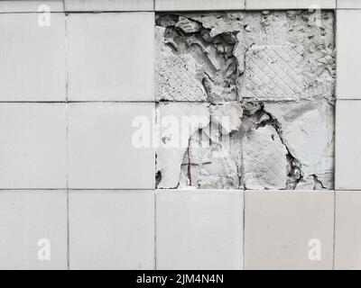 A wall with a broken off gray tile from the wall in full screen Stock Photo