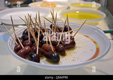 violet olives heap in oil on the white plastic plate closeup, delicious exotic food diversity Stock Photo